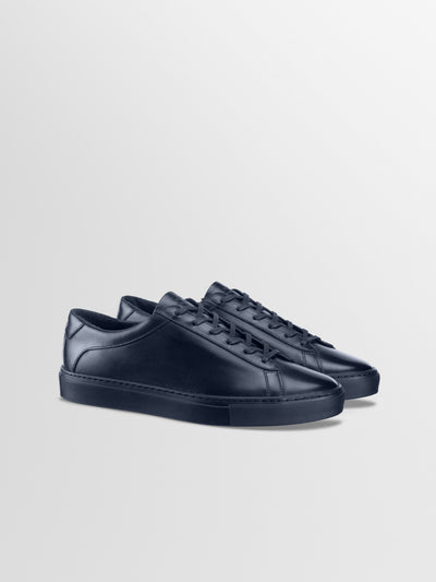 Men's Italian dark navy blue leather low-top sneakers with matching laces and soles, displayed on a clean light gray background.